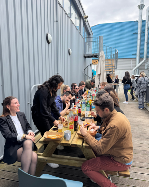 Photo des collaborateurs en train de partager un repas en extérieur.